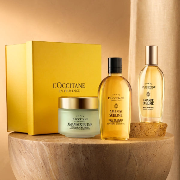 L'OCCITANE skincare products including a box, cream, and two bottles on a wooden surface with a beige background.
