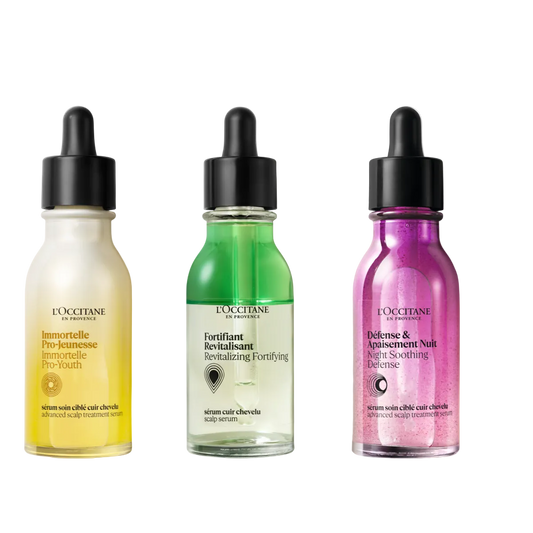 Three L'Occitane hair serum bottles in yellow, green, and pink on a white background